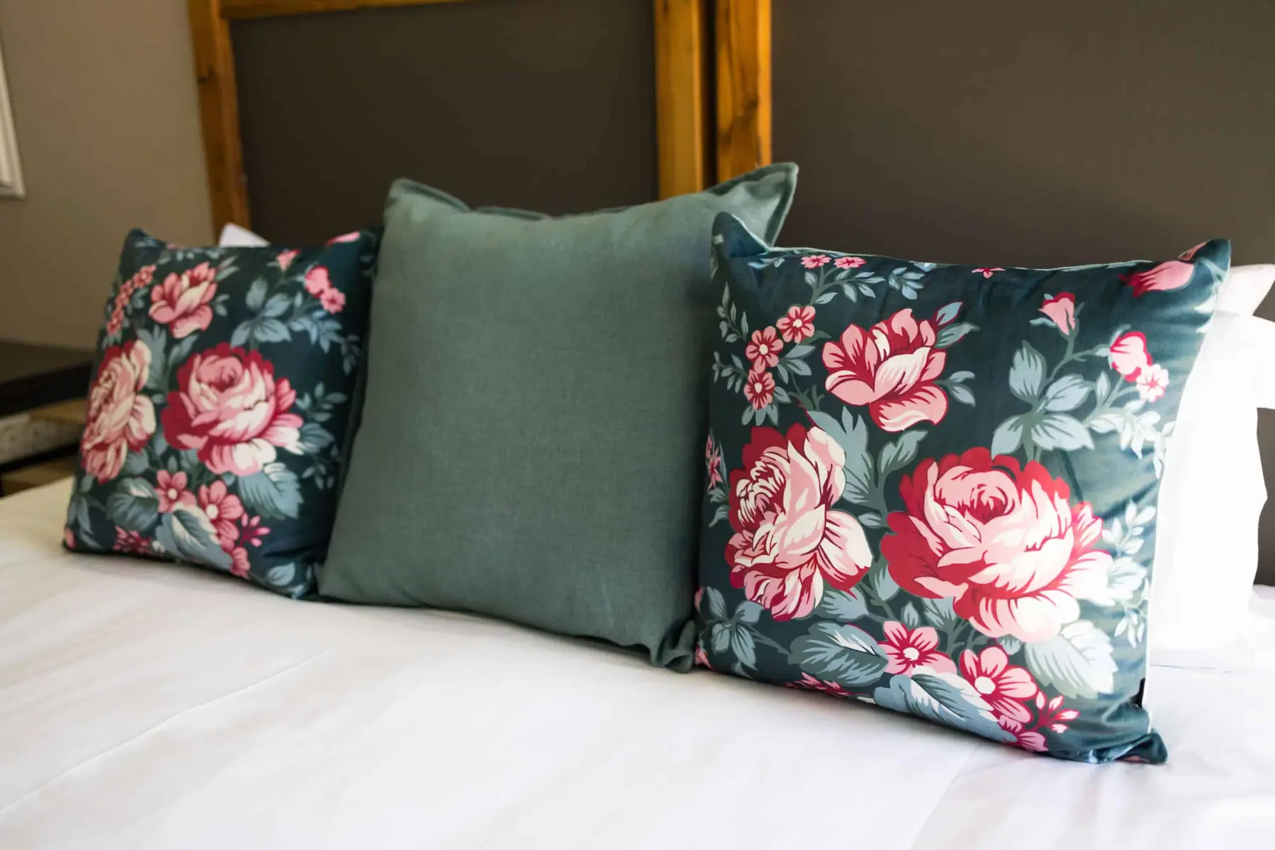 Floral and green cushions on a made bed at Best Rest Guesthouse